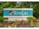 Welcoming Woodlake Village sign surrounded by colorful flowers and lush greenery at 404 Snowy Egret Dr., Murrells Inlet, SC 29576