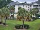 Exterior view of condo buildings surrounded by lush landscaping and palm trees, with a community pool visible at 477 White River Dr. # 32-H, Myrtle Beach, SC 29579