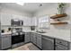 Bright kitchen features stainless steel appliances, gray lower cabinets, and open wood shelving at 6015 Catalina Dr. # 534, North Myrtle Beach, SC 29582