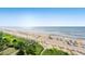 Panoramic beach view with the ocean, beach umbrellas, and greenery at 7100 N Ocean Blvd. N # 601, Myrtle Beach, SC 29572