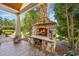 Charming stone fireplace on a covered patio, creating a cozy outdoor gathering spot with seating and serene backyard views at 784 Caines Landing Rd., Conway, SC 29526