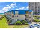 Multi-story building with light beige siding and blue roof, balconies, and well-maintained landscaping at 9660 Shore Dr. # 208, Myrtle Beach, SC 29572
