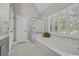 Bright bathroom features a soaking tub, walk-in shower, and shuttered windows that let in natural light at 15 Cherbourg Ct., Pawleys Island, SC 29585