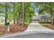 Home featuring long driveway leading to garage, mature trees, and adjacent landscaping at 15 Cherbourg Ct., Pawleys Island, SC 29585