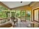 Relaxing screened porch with wicker rocking chair and a view of the lush backyard at 15 Cherbourg Ct., Pawleys Island, SC 29585