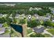 An aerial view of a neighborhood showcases the home's location with lush greenery, a pond, and nearby amenities at 176 Whispering Oaks Dr., Longs, SC 29568