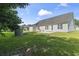 View of the home's backyard with a grass lawn, patio, and brick fire pit under a blue sky at 176 Whispering Oaks Dr., Longs, SC 29568