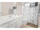 The bathroom has a white vanity, toilet, mirror and shower with black and white curtain at 176 Whispering Oaks Dr., Longs, SC 29568