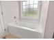 Bright bathroom features a white tub with window, tile surround, and pink walls at 176 Whispering Oaks Dr., Longs, SC 29568