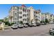 Three-story condo building featuring gray siding, white trim, a red roof, and ample parking at 186 Ella Kinley Circle # 101, Myrtle Beach, SC 29588