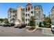 Three-story condo building with gray siding, white trim, and a red roof, surrounded by lush landscaping at 186 Ella Kinley Circle # 101, Myrtle Beach, SC 29588