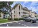 Beige condo with covered patios, landscaping, an asphalt parking lot, with blue sky and green trees in the background at 1900 Duffy St. # H-8, North Myrtle Beach, SC 29582
