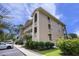 Beige condo with covered patios, landscaping, an asphalt parking lot, with blue sky and green trees in the background at 1900 Duffy St. # H-8, North Myrtle Beach, SC 29582