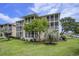 Beige condo with covered patios and screened-in porches, lush landscaping, green grass and mature trees at 1900 Duffy St. # H-8, North Myrtle Beach, SC 29582