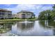 A scenic view of a pond with a fountain in front of beige condos with covered patios and green grass and shrubbery at 1900 Duffy St. # H-8, North Myrtle Beach, SC 29582