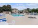 Community pool and hot tub area with lounge chairs and tables surrounded by beige condos under a partially cloudy sky at 1900 Duffy St. # H-8, North Myrtle Beach, SC 29582
