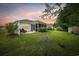 Picturesque backyard with a lush lawn, mature landscaping, a patio, and a screened porch at sunset at 208 Hamilton Way, Conway, SC 29526