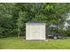 Close-up of a well-maintained yellow and white storage shed in a spacious backyard with trailer parked beside it at 208 Hamilton Way, Conway, SC 29526