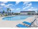 Relaxing community pool area surrounded by lounge chairs, palm trees and blue umbrellas under a sunny sky at 3129 Palma Way, Myrtle Beach, SC 29579