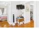 Hallway featuring wood floors, a TV mounted on the wall, a wooden table, and open doors leading to bedrooms at 401 17Th Ave. S, North Myrtle Beach, SC 29582