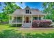 Charming home with an expansive front porch, red front door, manicured lawn and surrounding trees at 5113 Pee Dee Ln., Murrells Inlet, SC 29576
