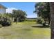 Expansive backyard featuring a lush green lawn, trees, and a view of the marsh in the distance at 5460 Huntington Marsh Rd., Murrells Inlet, SC 29576