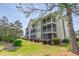Exterior view of condo featuring screened-in elevated decks, green siding, and lovely landscaping at 5852 Longwood Dr. # 302, Murrells Inlet, SC 29576