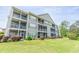 Exterior view of condo featuring screened-in elevated decks, green siding, and lovely landscaping at 5852 Longwood Dr. # 302, Murrells Inlet, SC 29576