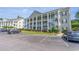 Three-story condo building featuring elevated decks, white columns, and lush landscaping at 5852 Longwood Dr. # 302, Murrells Inlet, SC 29576