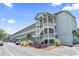 Exterior view of the building with multiple levels and outdoor staircases, complemented by landscaping and parking at 5905 South Kings Hwy. # 5202, Myrtle Beach, SC 29575