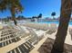 A sunny pool deck with a row of white lounge chairs and several palm trees at 6001 S Kings Hwy., Myrtle Beach, SC 29575