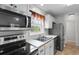 Well-lit kitchen showcasing stainless steel appliances, white cabinets, and double sink under a window at 6500 Colonial Dr. # 2, Myrtle Beach, SC 29572