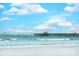 Beach view with a wooden pier stretching over the ocean waves under a blue, cloudy sky at 67 Bossie Ln., Georgetown, SC 29440
