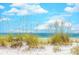 Gorgeous beach view with white sand, dunes, sea grass, and sparkling ocean water under a blue sky with puffy white clouds at 67 Bossie Ln., Georgetown, SC 29440