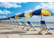Beach scene with blue and yellow sun umbrellas and blue and white lounge chairs near the ocean under a sunny, cloudy sky at 67 Bossie Ln., Georgetown, SC 29440