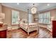 The primary bedroom offers a decorative light fixture, hardwood floors, and bright windows at 9 Winnowing Way, Pawleys Island, SC 29585