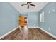 Blue bedroom featuring three windows, ceiling fan, wood grain flooring, and view to bathroom at 1039 Forest Dr., Conway, SC 29526