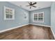 Light blue bedroom featuring three windows, a ceiling fan, wood grain flooring, and neutral trim at 1039 Forest Dr., Conway, SC 29526