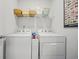 Functional laundry room with a white washer and dryer, complemented by storage shelves and wall decor at 1723 Perthshire Loop, Myrtle Beach, SC 29579