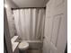Bathroom with a shower-tub combo with a white curtain, toilet, and white brick-patterned walls at 1903 Rose St., Conway, SC 29527