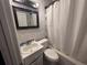 Bathroom with a shower-tub combo with a white curtain, toilet, sink, vanity, mirror, and white brick walls at 1903 Rose St., Conway, SC 29527
