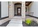 Charming front entrance with stone pillars, a wood front door, and manicured landscaping at 2205 Yellow Morel Way, Myrtle Beach, SC 29579