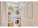 Compact laundry area with stacked washer and dryer, storage shelves, and a white door at 4396 Baldwin Ave. # 1, Little River, SC 29566