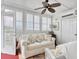 Cozy sunroom with a white couch, wicker chair, and multiple windows with white shutters at 4396 Baldwin Ave. # 1, Little River, SC 29566