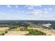 Wide aerial shot reveals a home nestled among green fields, ponds, and wooded landscape beneath a blue sky at 4860 Highway 378, Conway, SC 29527