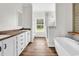 Modern bathroom boasts dual vanities, wood-look floors, and a luxurious soaking tub near a shower with stylish tile work at 565 Kent Rd., Georgetown, SC 29440