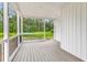 Covered front porch featuring wood-look flooring and black railings, offering a welcoming outdoor space with wooded views at 565 Kent Rd., Georgetown, SC 29440