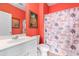 Cozy bathroom with a vibrant coral color, white vanity and toilet, and beach-themed shower curtain at 604 Heathrow Dr. # 1101, Myrtle Beach, SC 29579