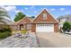 Charming brick home featuring a two-car garage, well-maintained landscaping, and outdoor seating area on a brick driveway at 702 Compass Point Dr., North Myrtle Beach, SC 29582