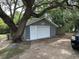 Detached garage featuring both a roll-up door and a side door, nestled near a large shade tree at 7708 Woodland Dr., Myrtle Beach, SC 29572